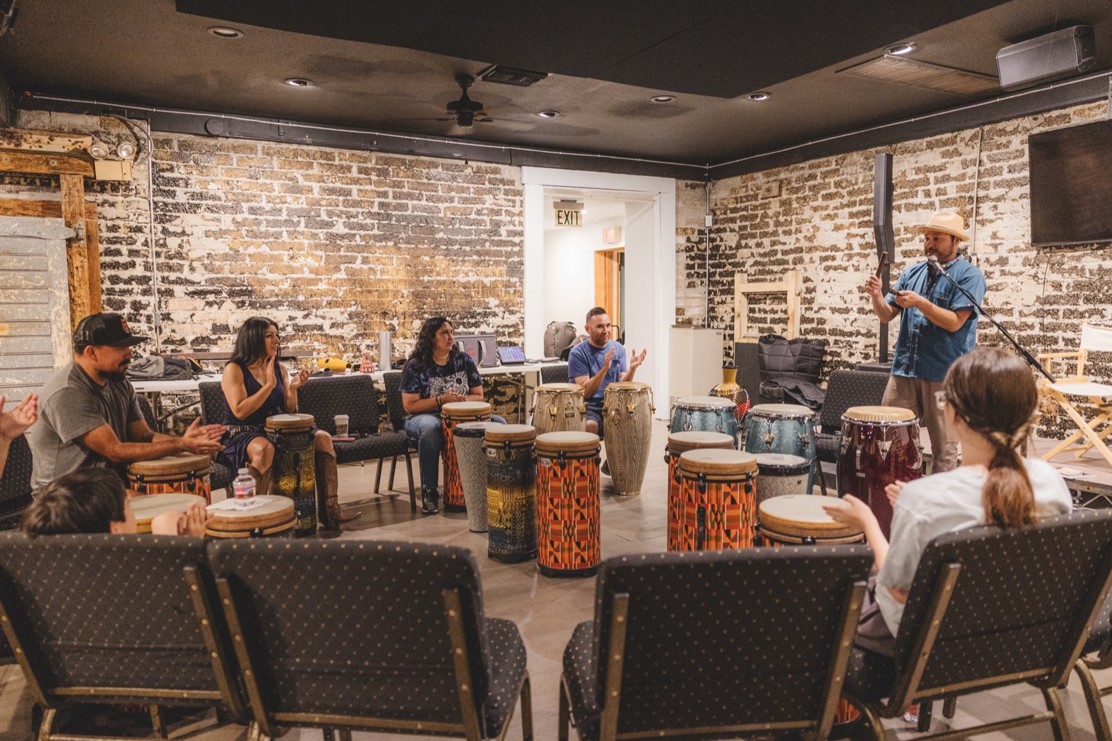 Carlos leading a Latin Rhythms workshop with participants seated around congas